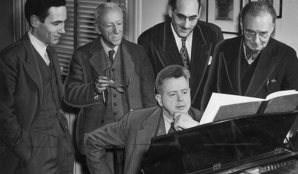 Sir Ernest MacMillan at the piano with Godfrey Ridout, Prof. Leo Smith, John Weinzweig and Dr. Healey Willan surrounding him. The photograph was taken circa. 1948 by Nott and Mell.
